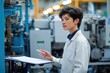 © Pete - Young factory worker presents production development results indoors. Focused adult presents documents near industrial machinery. Business presentation in modern factory. Person wearing white lab
