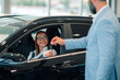 © Zamrznuti tonovi - Woman in glasses smiling, receiving car keys from suited man in a dealership