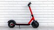 © Eakkarin - a photostock of a single electric scooter parked against a clean white wall, urban commuting 2025