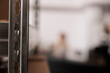 Wall Mural - Selective focus of storehouse shelves full with boxes, in background employee working at counter desk, checking clients online orders. Warehouse manager preparing packages for delivery