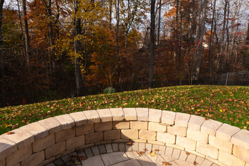 Wall Mural - A serene backyard featuring a curved stone patio surrounded by vibrant autumn foliage, creating a peaceful outdoor space ideal for relaxation and nature appreciation.