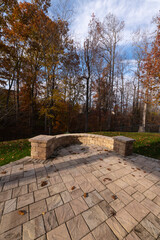 Wall Mural - A serene backyard featuring a curved stone patio surrounded by vibrant autumn foliage, creating a peaceful outdoor space ideal for relaxation and nature appreciation.