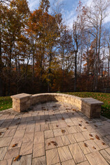 Wall Mural - A serene backyard featuring a curved stone patio surrounded by vibrant autumn foliage, creating a peaceful outdoor space ideal for relaxation and nature appreciation.