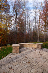 Wall Mural - A serene backyard featuring a curved stone patio surrounded by vibrant autumn foliage, creating a peaceful outdoor space ideal for relaxation and nature appreciation.