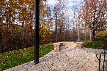 Wall Mural - A serene backyard featuring a curved stone patio surrounded by vibrant autumn foliage, creating a peaceful outdoor space ideal for relaxation and nature appreciation.