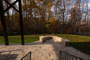 Wall Mural - A serene backyard featuring a curved stone patio surrounded by vibrant autumn foliage, creating a peaceful outdoor space ideal for relaxation and nature appreciation.