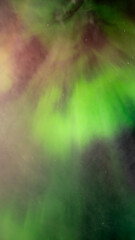 Wall Mural - vertical panorama of red and green radiating aurora in a starry night sky