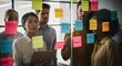 © Kenny - Group of coworkers brainstorming with sticky notes on a glass wal