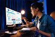 © Summit Art Creations - Smiling young beautiful asian creative looking on pc of profit of sales target report and writing on notebook for memo with planning invest new strategy market project at neon light night. Stratagem.