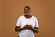 © Prostock-studio - Portrait of excited emotional young curvy African American woman smiling and laughing looking at camera while standing isolated over brown wall. Cheerful chubby lady posing, hearing good news