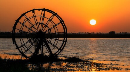 Poster - Serene Sunset Over Water Wheel Silhouette at Calm Water Body