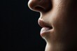 © JAKE STUDIO - A close-up of a person's face, focusing on the profile, highlighting the lips and skin texture against a dark background.