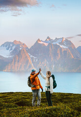 Wall Mural - couple man and woman traveling together hiking in norway, friends high five hands in mountains activ