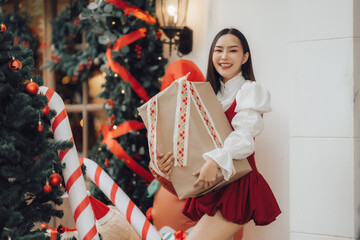 Christmas Cheer: A young woman beams with delight, cradling a large gift against a backdrop of festive Christmas decor. The image evokes the spirit of the season and the joy of giving.