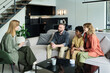 © pressmaster - Family counseling session in modern, minimalistic living room. Family sitting on couch beside counselor engaging in discussion surrounded by contemporary decor in spacious home interior