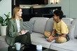 © pressmaster - Therapist sitting on couch in modern office engaging with young patient. Couch in foreground with office setting in background, promoting mental health care