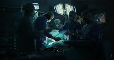 Poster - Diverse Surgical Team Working in a Darkened Operating Room Surrounded by Advanced Medical Equipment. Doctors Performing a Complex Surgery with the Help of Laparoscopic Equipment