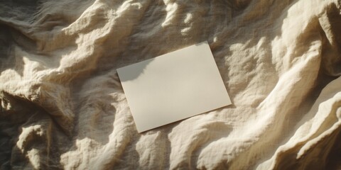 Poster - Blank paper sheet card positioned on a crumpled beige bed blanket, creating a mockup copy space. The soft warm sunlight shadows enhance the aesthetic minimal brand template in this flat lay setup.