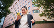 © peopleimages.com - Business woman, smartphone and luggage on travel in city with contact, happy and low angle on urban sidewalk. Person, phone and corporate lawyer with booking taxi, networking and baggage in Japan