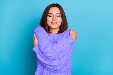 Wall Mural - portrait of attractive dreamy cheerful girl hugging herself isolated over bright blue color backgrou