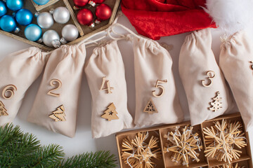 Christmas advent calendar with gift velvet bags and wooden numbers on a white background. Eco-friendly