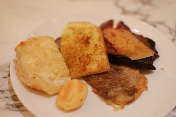 French toast with fried meat and potato chips on a white plate.