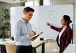 © Running opossum - Asian female leading business presentation with caucasian male colleague taking notes