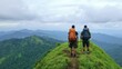 © Naree - Two hikers stand atop a lush green hill, overlooking a vast mountainous landscape under a cloudy sky.