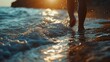 © ABIDZAR ALFAREZ - Person walking barefoot on beach at sunset, waves splashing around feet.