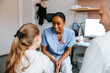 © Maskot - Smiling young doctor talking with girl patient in medical examination room at clinic