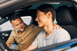 © Maskot - Smiling young man getting driving lessons from father while sitting in car