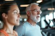 © Milos - An elderly man and woman portray unity and strength at the gym, exemplifying a loving partnership and commitment to fitness and health, inspiring others around them.