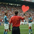 © LIDIIA - Referee holding heart card. A soccer referee in a red shirt holds up a red heart-shaped card on the field, with players and a crowd in the background.