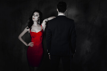 Poster - Portrait of brunette lady with curly hair in violet dress with bijoutery looking to the side holding hand on waist lean on shoulder of latin gigolo man with rear back view isolated on grey background