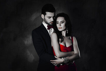 Poster - Portrait of naughty couple embracing looking at each other, man with bristle in tux with bowtie pretty charming woman with curls isolated on grey background