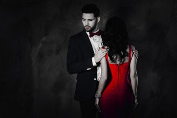 Poster - Rear view of pretty brunette woman with curly hair booty bum harsh man in tux with bow holding hands on shoulders of lover attractive couple isolated on grey background with copy space empty place