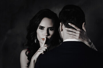 Poster - Portrait of tempting brunette lady showing silence sign with forefinger touching secret mysterious gentlemen with rear view, lovely Mr and Mrs isolated on grey background