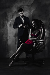 Poster - Portrait of sexual hot woman in purple dress sitting in leather chair trendy man unbutton jacket looking at bitch having erection lovely attractive couple isolated on grey dark background