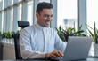 © Rgfx - Middle Eastern male manager working on a laptop computer in a modern office.