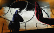 © IKON Images - Hand stopping mother and child at razor wire border