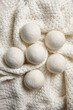© mikeosphoto - Set of wool dryer balls arranged on a soft, textured knit fabric, top view, flat lay. Eco-friendly laundry accessory designed to reduce drying time, static, and wrinkles naturally