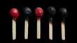 © Azis Stock - Five used matches in a row, alternating between red and black burnt heads, on a black background.