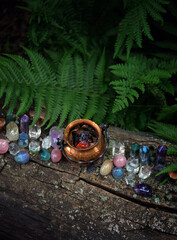 Wall Mural - colorful gemstone crystals and witch copper cauldron in forest, natural background. occult esoteric ritual, witchcraft, spiritual practice. fairytale atmosphere. top view