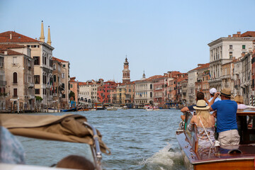 Rear view of group of tourists sailing on tour boat on Grand Canal next to Church of San Bartolomeo di Rialto in a sunny summer day in Venice. Soft focus. Copy space. Travel in Italy theme.