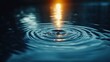 © irawan710 - Water droplet impact, creating concentric ripples illuminated by warm light.