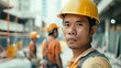 © Z A C - A construction worker in a yellow hard hat with a blurred background Of a construction site.
