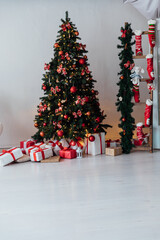 Wall Mural - Christmas tree with gifts decorated with red toys garlands in the interior