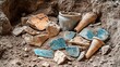 © irawan710 - Unearthed ancient pottery shards and vessels in archaeological dig site.