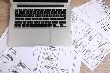 Leinwandbilder - Developing UI design. Sketches of website wireframes and laptop on wooden table, top view
