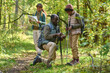 © AnnaStills - African American father kneeling next to son and teaching him how to use compass while his older kid exploring map in background